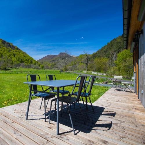 a table and chairs sitting on a wooden deck at La Dormeuse du Val in Chambon-sur-Lac