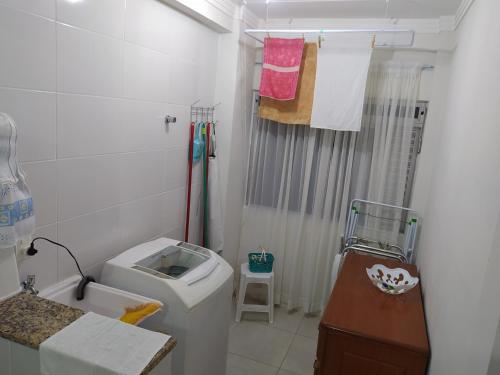a bathroom with a toilet and a sink and towels at AP Itapema in Itapema