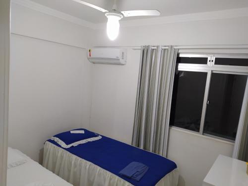 a room with two beds and a window with a ceiling fan at AP Itapema in Itapema