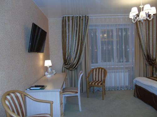 Habitación de hotel con escritorio, cama y habitación en Domashny Ochag, en Ujtá