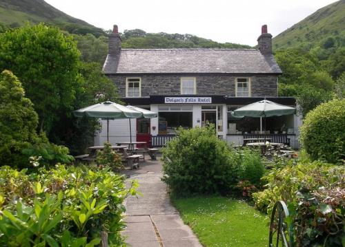 Bryn-crug的住宿－多爾格施住宿加早餐旅館，前面有桌子和伞的建筑