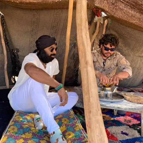 two men sitting on a bed in a tent at Sunset luxury camp in Hassilabied