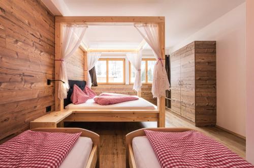 two beds in a room with wooden walls at Gitschberg - Appartements in Vandoies