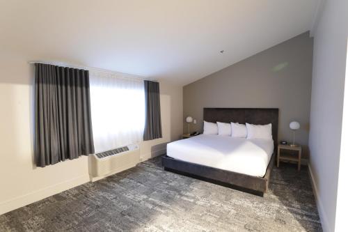 a bedroom with a white bed and a window at Lake Placid Inn Boutique Hotel in Lake Placid