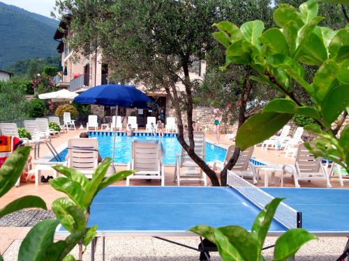 a swimming pool with chairs and a blue table and umbrella at Residence Erika in Tignale