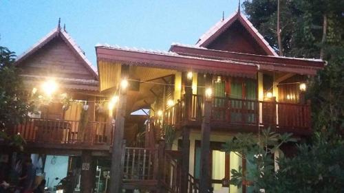 a large wooden house with a deck at night at Sukjai Homestay in Chiang Mai