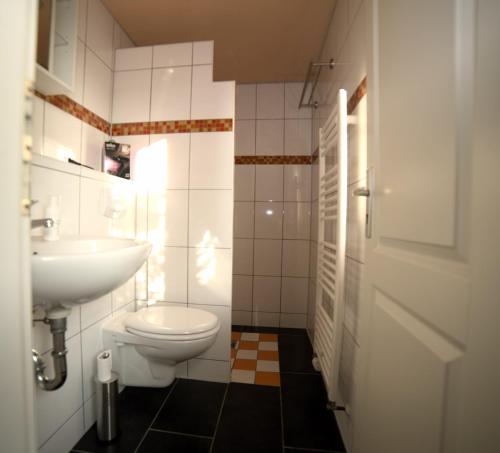 La salle de bains est pourvue de toilettes blanches et d'un lavabo. dans l'établissement Ferienhaus Nordstrand, à Altenkirchen