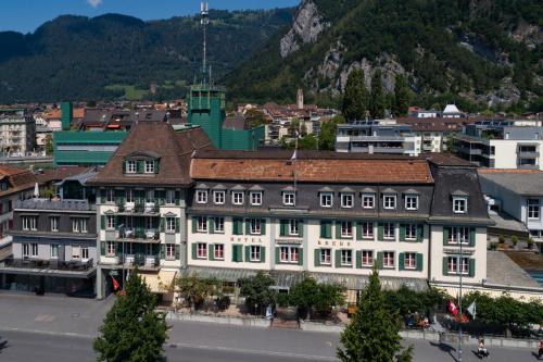 ein Gebäude in einer Stadt mit einem Berg im Hintergrund in der Unterkunft Hotel Krebs Interlaken in Interlaken