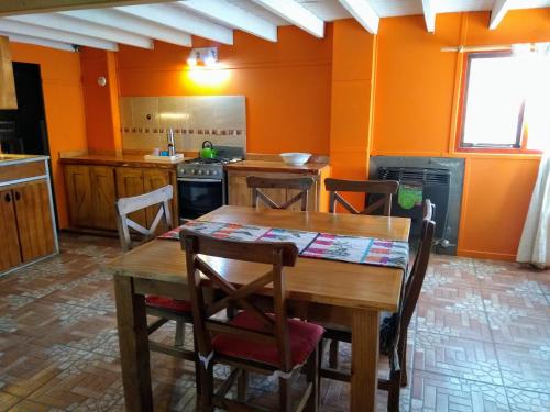 a kitchen with orange walls and a wooden table and chairs at Casa Patagónica Los Charitos in El Chalten