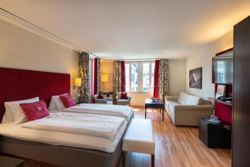 Habitación de hotel con 2 camas y sala de estar. en Hotel Krebs Interlaken en Interlaken