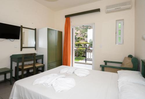a bedroom with a bed and a desk and a window at Aretousa in Sougia