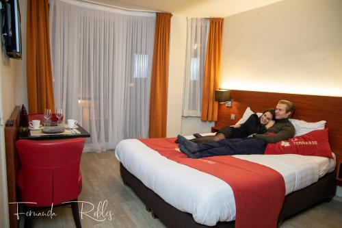 two people laying on a bed in a hotel room at Hotel La Terrasse in De Panne