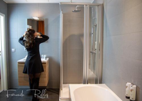 a woman standing in front of a shower in a bathroom at Hotel La Terrasse in De Panne