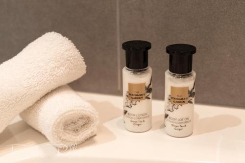 two bottles of shampoo and towels on a bathroom sink at Hotel La Terrasse in De Panne