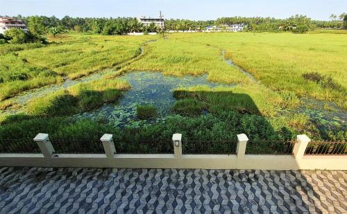 a view of a field with a fence and a river at Nessies Nagaon in Alibaug