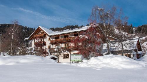 a large house in the snow with a sign in front at Hotel Ucliva in Waltensburg