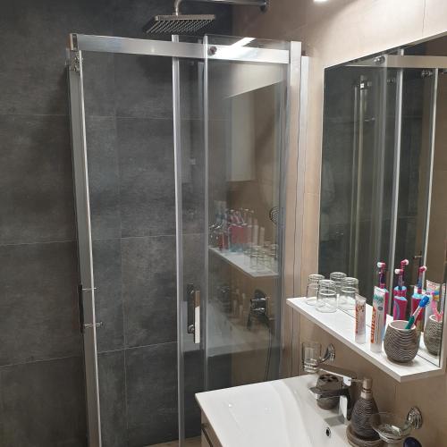 a bathroom with a shower with a sink and a mirror at Apartman Noalux Kopaonik in Kopaonik