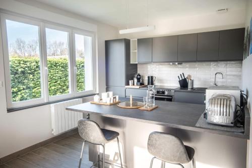 - une cuisine avec un comptoir et deux tabourets dans l'établissement Passepierre villa rénovée à l'orée de la zone naturelle, à Groffliers