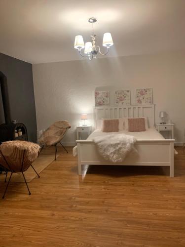 a bedroom with a white bed and a chair at Agro na Wapniarni in Białla