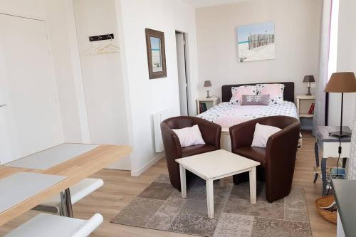 a bedroom with a bed and two chairs and a table at Studio Cosy LES ROSES TREMIERES 3 étoiles centre Plouharnel proche mer in Plouharnel