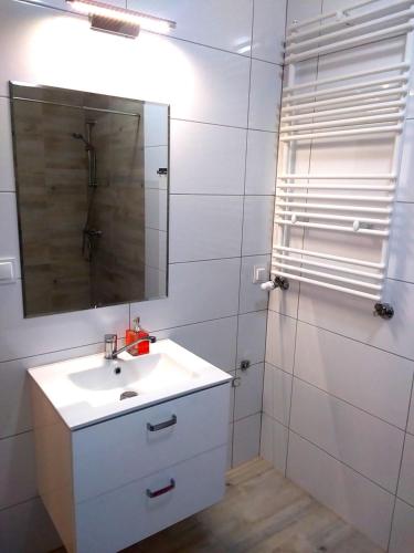 a white bathroom with a sink and a mirror at Welcome Cozy Apartment Old Town in Elblag