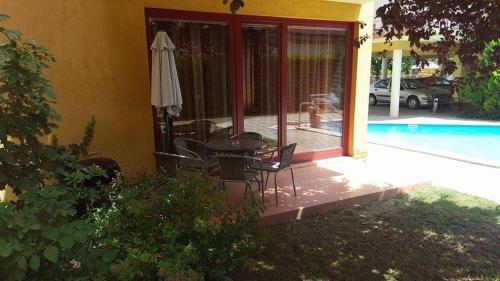 een patio met een tafel en een parasol naast een huis bij Jenny apartman Siófok in Siófok