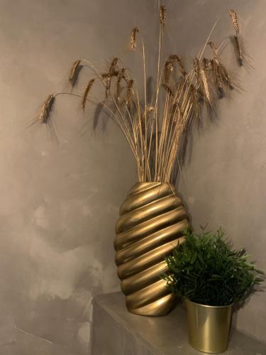 a gold vase with grass in it next to two plants at Agro na Wapniarni in Białla