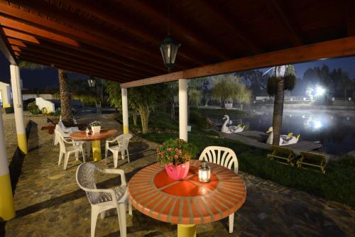 a patio with tables and chairs and a view of a lake at Herdade do Sardanito da Frente in Zambujeira do Mar