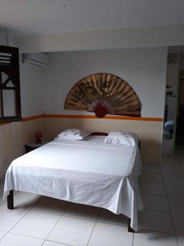 1 dormitorio con cama blanca y cabecero de madera en petit coin tranquille, en Les Trois-Îlets