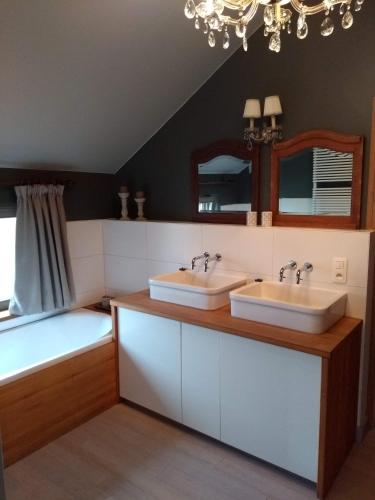 a bathroom with two sinks and a tub and a chandelier at Vakantiehuis Louiselotte in Alveringem
