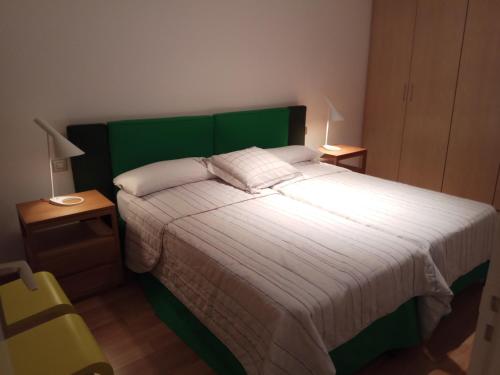 a bedroom with a bed with a green headboard and two lamps at APARTAMENTO MIRADOR DEL CADI in Puigcerdà