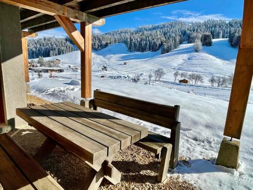a wooden bench sitting on a porch with a snow covered field at Gîte avec terrasse et belle vue - ChaletNelda com in Lamoura