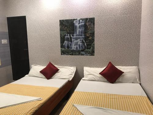 two beds with red pillows in a room at Rehoboth Home Stay in Kanyakumari