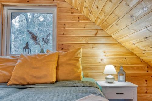 a bedroom with wooden walls and a bed with yellow pillows at Valkla Puhkekeskuse saunamaja in Kuusalu