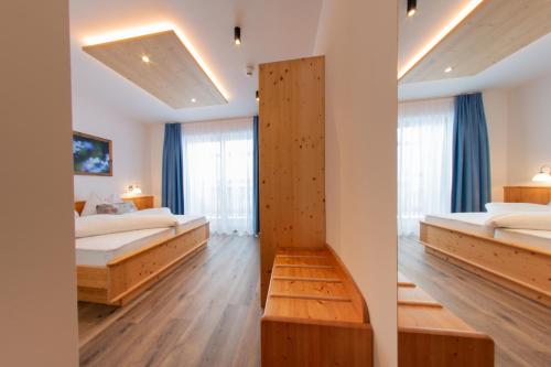 a bedroom with two beds and a large window at Hotel Gran Pre in San Vigilio Di Marebbe