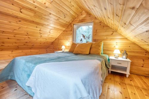 ein Schlafzimmer mit einem Bett in einer Holzhütte in der Unterkunft Valkla Puhkekeskuse saunamaja in Kuusalu