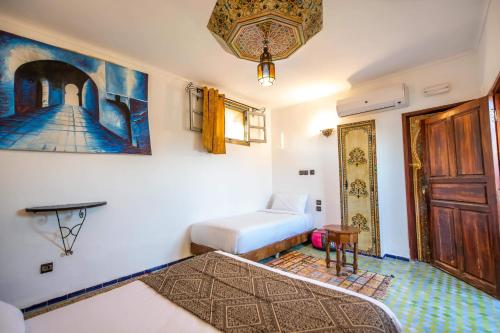 a bedroom with two beds and a door and a table at Le Cèdre D'argent in Fès