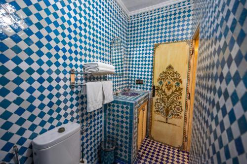 a bathroom with blue and white tiled walls and a toilet at Le Cèdre D'argent in Fès