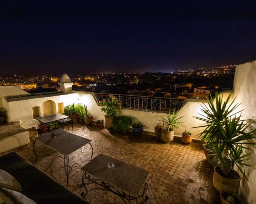 a balcony with tables and potted plants at night at Le Cèdre D'argent in Fès