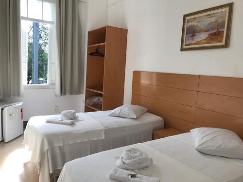 a hotel room with two beds with towels on them at Hotel Vila Real Rex in Poços de Caldas