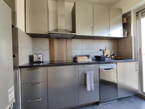 una cocina con electrodomésticos de acero inoxidable y armarios blancos en Legion Suite - Your perfect vacation !, en Niza