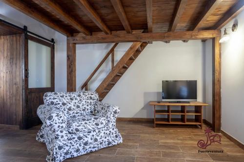 uma sala de estar com uma cadeira e uma televisão em Casa Emblemática "Casa del Cuartel" em La Oliva