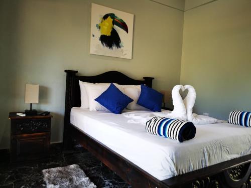 Una cama con almohadas azules y blancas y un cisne en Tuki Tuki Lodge, en Sámara