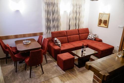 a living room with a red couch and a table at Vila Rajski kutak Kopaonik in Kopaonik