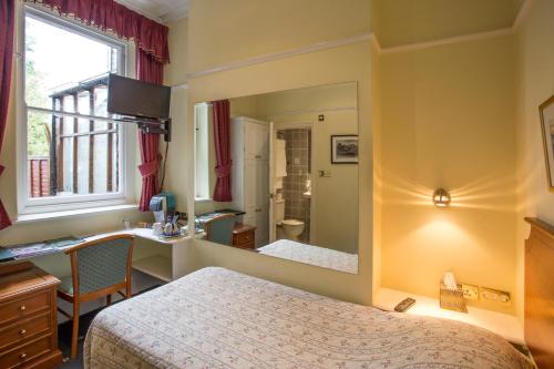 a room with two beds and a sink and a mirror at 9 Green Lane Bed and Breakfast in Buxton