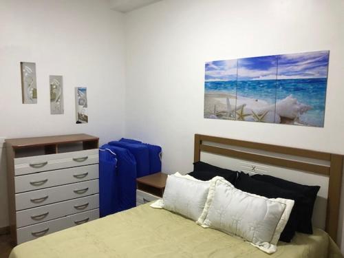 ein Schlafzimmer mit einem Bett, einer Kommode und einem Gemälde in der Unterkunft Flat Angra Inn 220 Angra dos Reis in Angra dos Reis