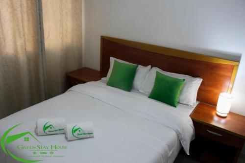 um quarto com uma cama branca e almofadas verdes em Green Stay house em Maputo