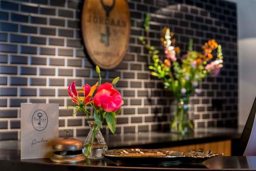 einem Tisch mit Blumenvasen und einer Uhr an der Wand in der Unterkunft Mr. Jordaan in Amsterdam