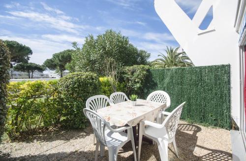 een tafel en stoelen op de patio van een huis bij LE SOUEHLA APPART - REZ de JARDIN Parking PISCINE Wi-Fi Proche plage - Résid les Sables D'or - TOP PROS SERVICESConciergerie La Grande Motte in La Grande-Motte