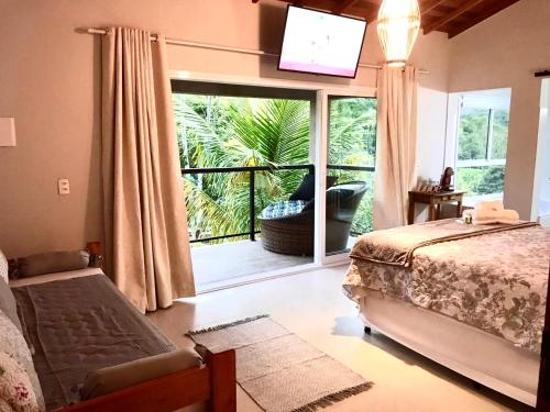 a bedroom with a bed and a large window with a balcony at Pousada Bezerra in Nazaré Paulista